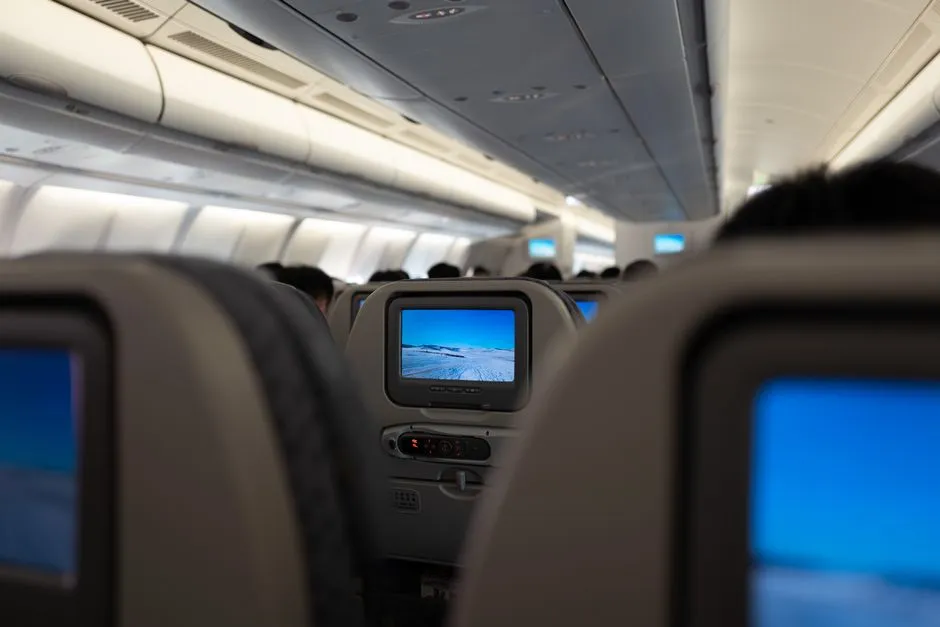 Airplane cabin interior with seat-back entertainment screens, illustrative photo