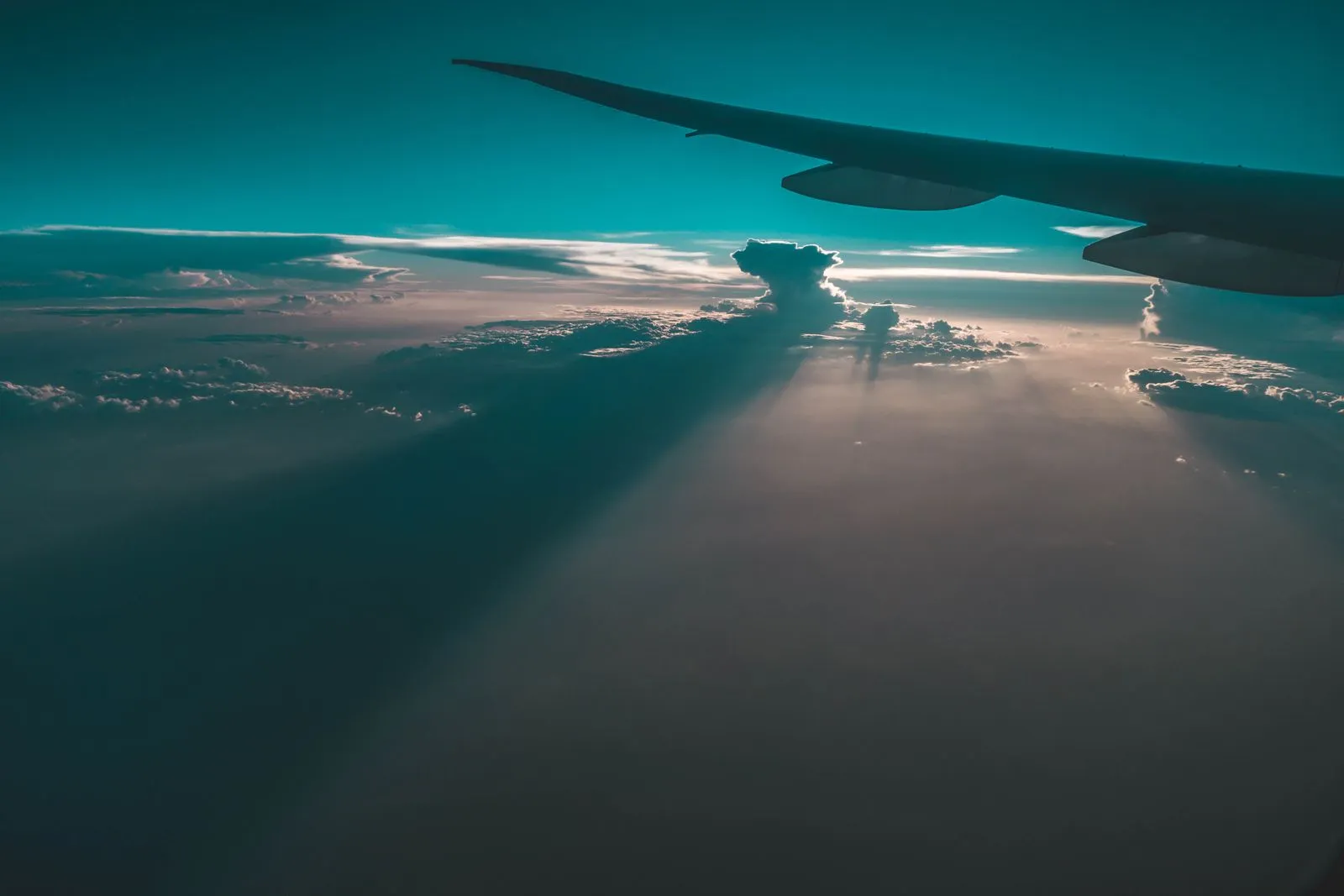 Airplane wing above the clouds at sunset, illustrative travel photo